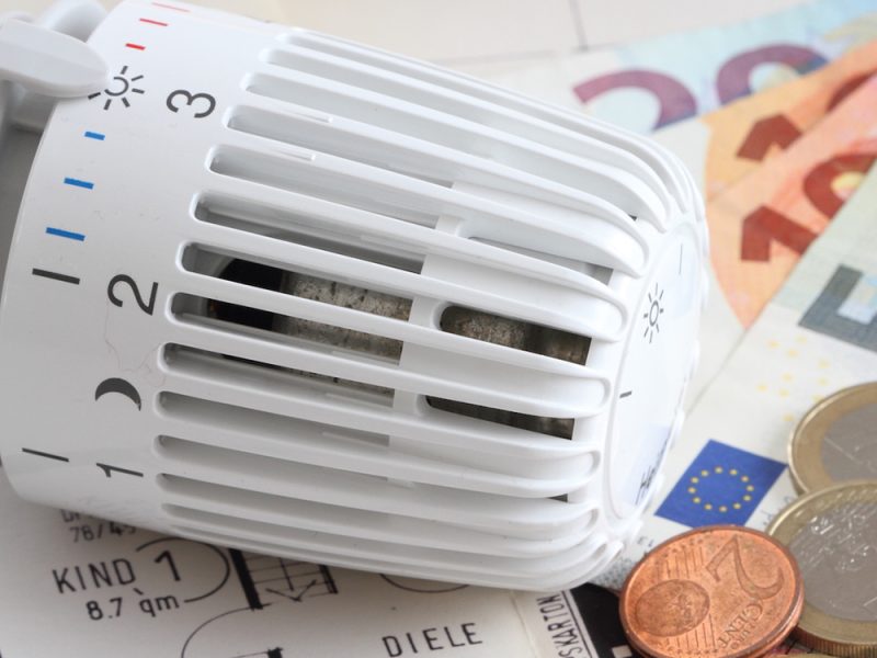 Heizungsthermostat mit Geldscheinen auf einem Bauplan